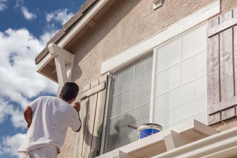 Professional house painter painting the trim and shutters of a home