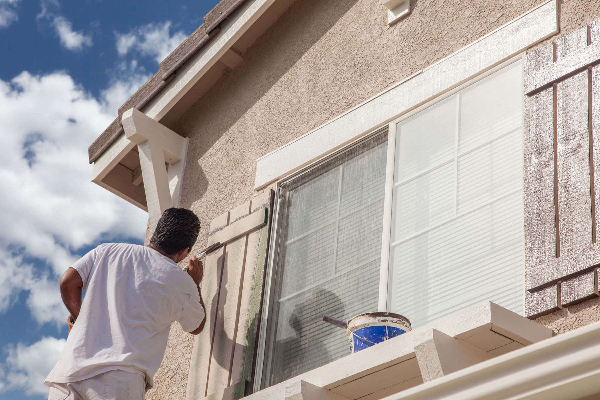 Professional house painter painting the trim and shutters of a home